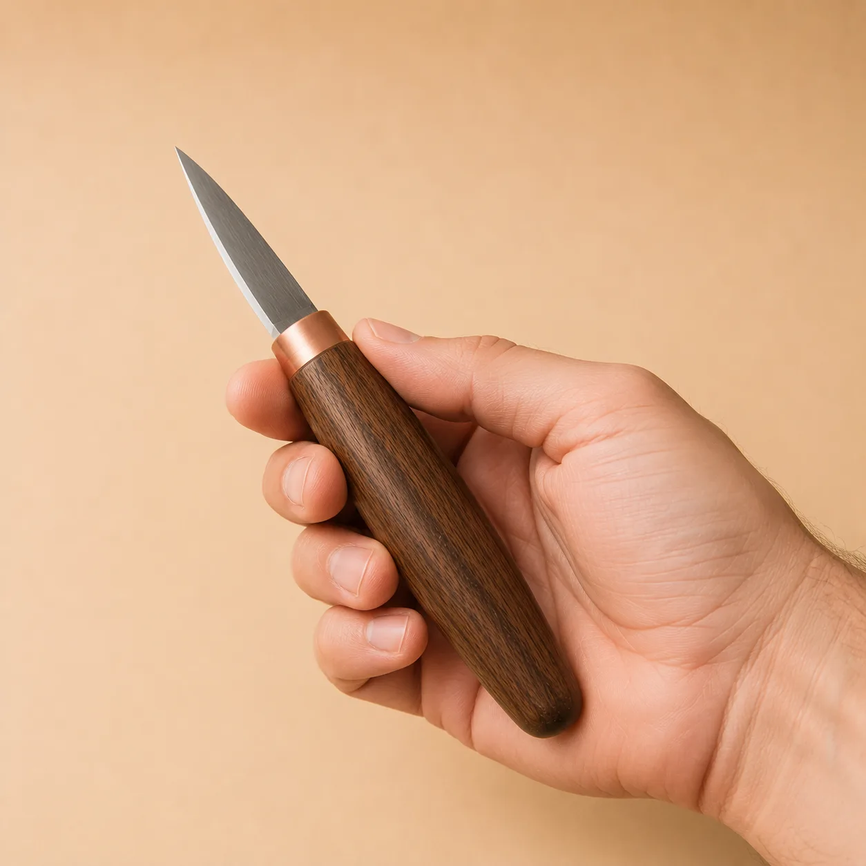 A carving knife held in an adult hand against a plain background, showing the real size of the walnut handle