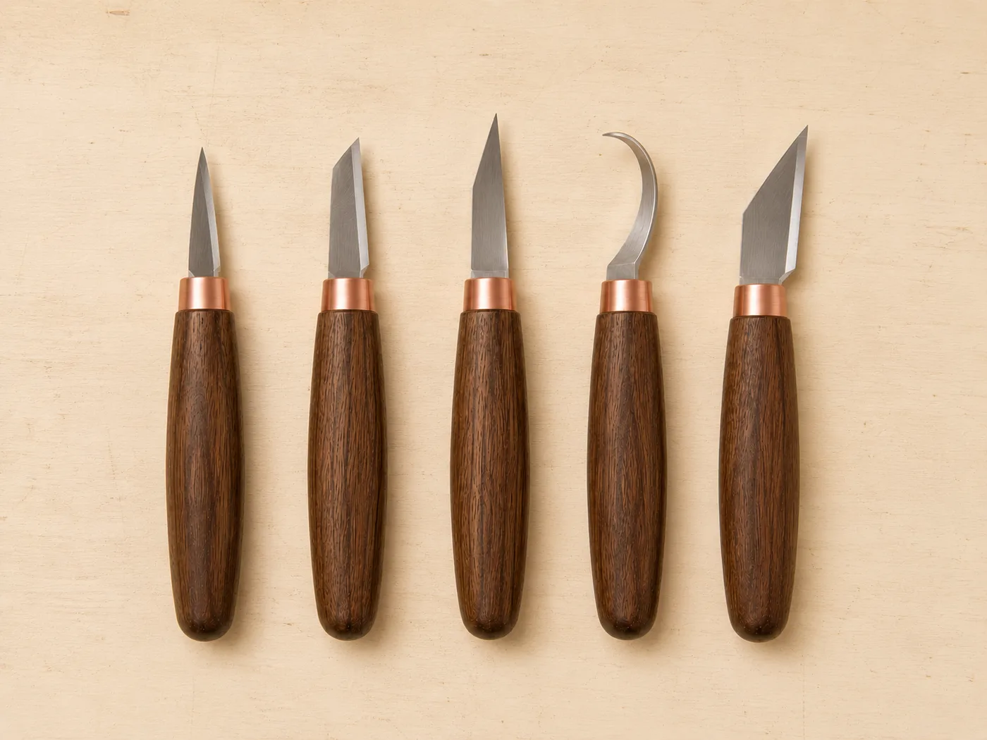 The five carving knives laid out in a row, seen from above, each blade profile clearly different from the next